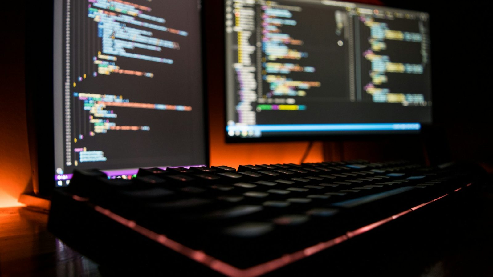 Dark workspace with multiple monitors displaying code.