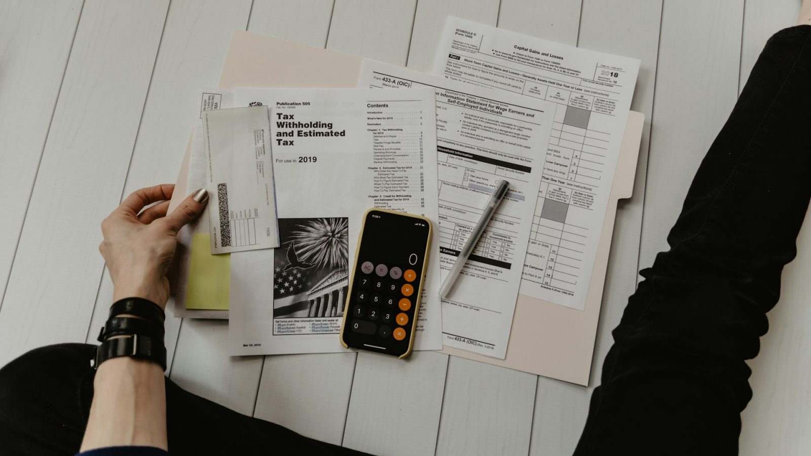 Printed documents, a calculator and a phone laid out on a desk.
